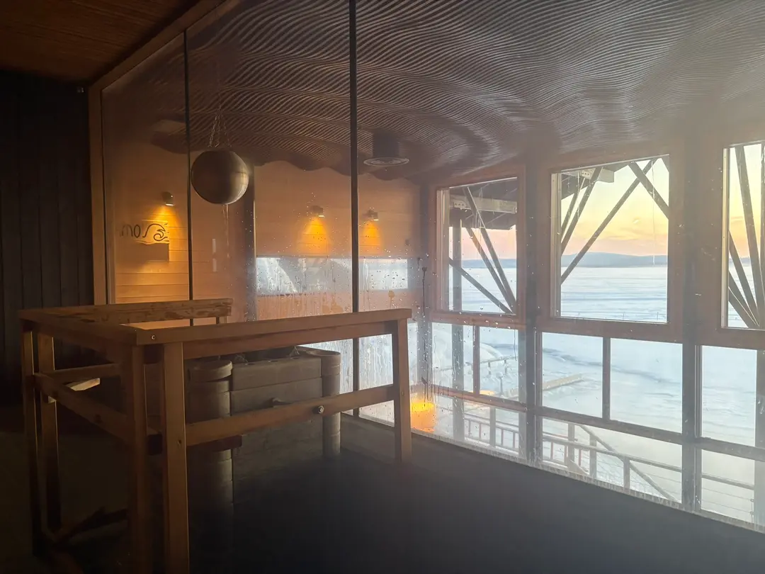 Wooden sauna with a panoramic window over the frozen lake