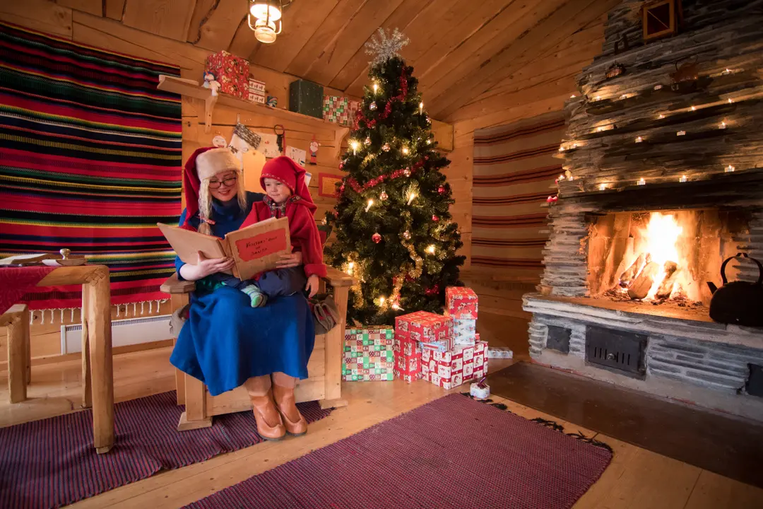 Reading a Christmas story by the fireplace in a cosy Lapland cabin