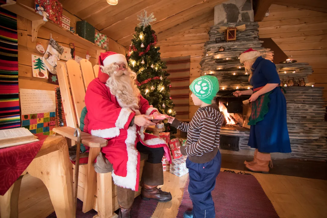 Santa handing a gift to a child during a private cabin visit